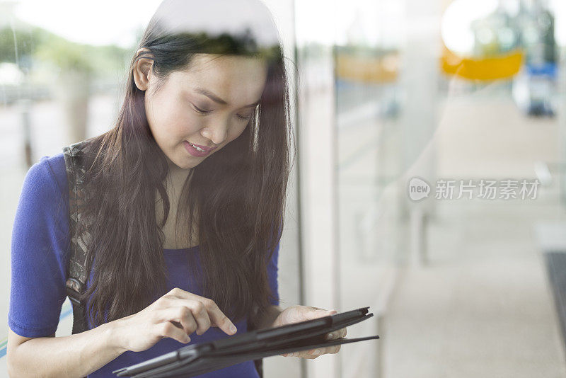 迷人的长发亚洲女子在机场候机厅使用平板电脑