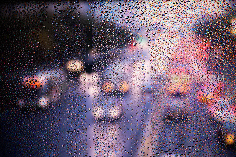 夜晚的城市灯光从一个下雨的窗户