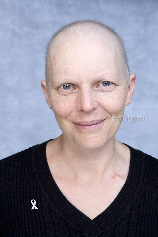 一位秃头患者戴着乳腺癌意识丝带。