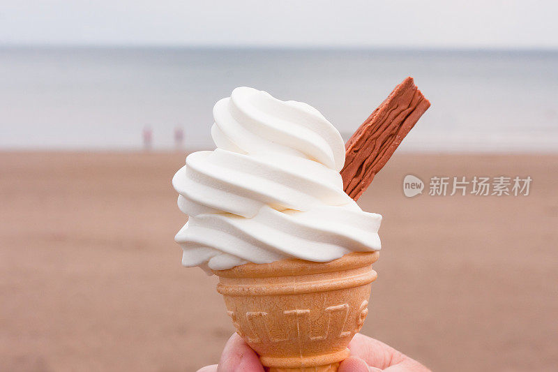 带巧克力片的蛋卷冰淇淋，背景是海滩