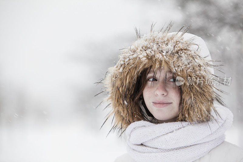 雪下穿着白色夹克的漂亮少女