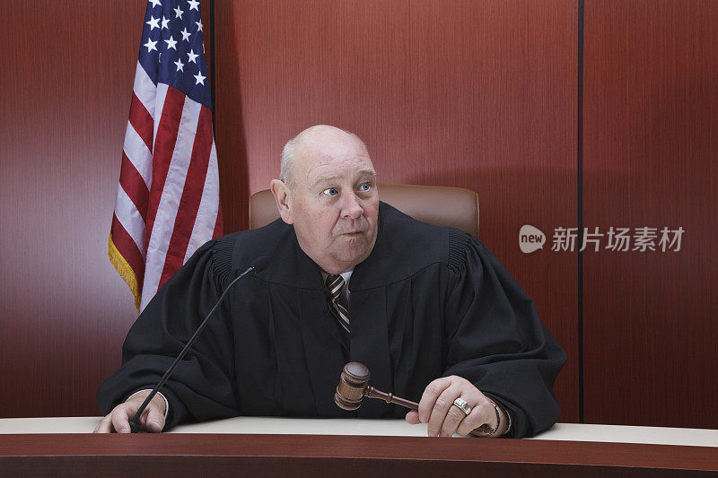 手持木槌的男法官坐在法庭上