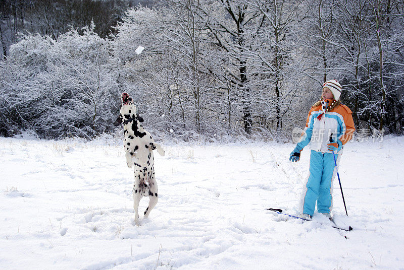 孩子和她的狗在雪中玩耍