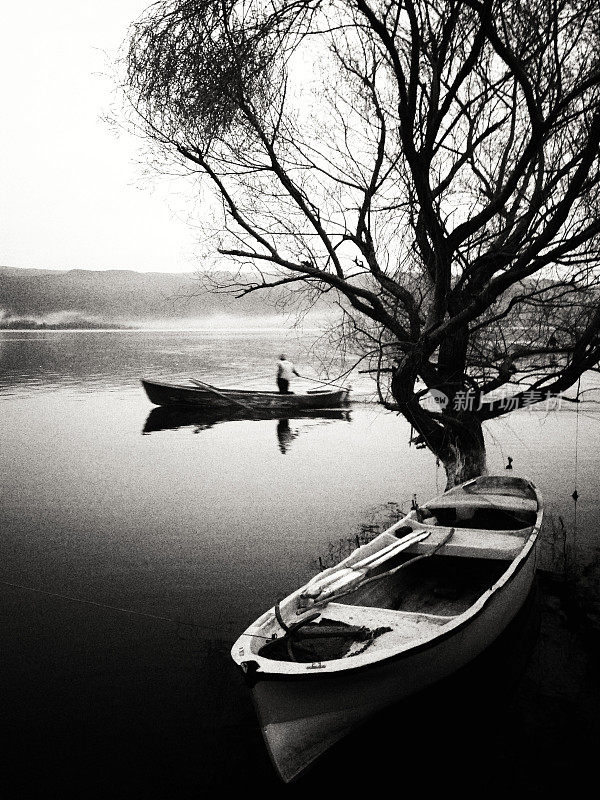 一个渔民在船上的黑白图像