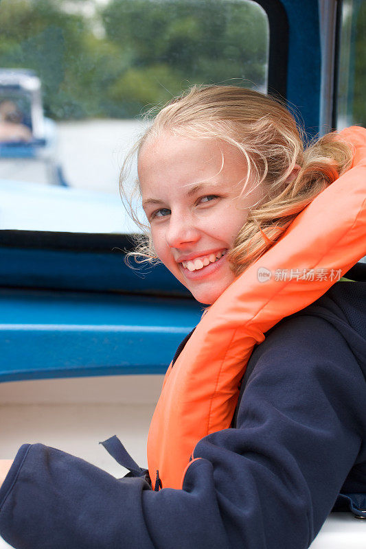 穿着救生衣的微笑女孩在一艘小船上航行