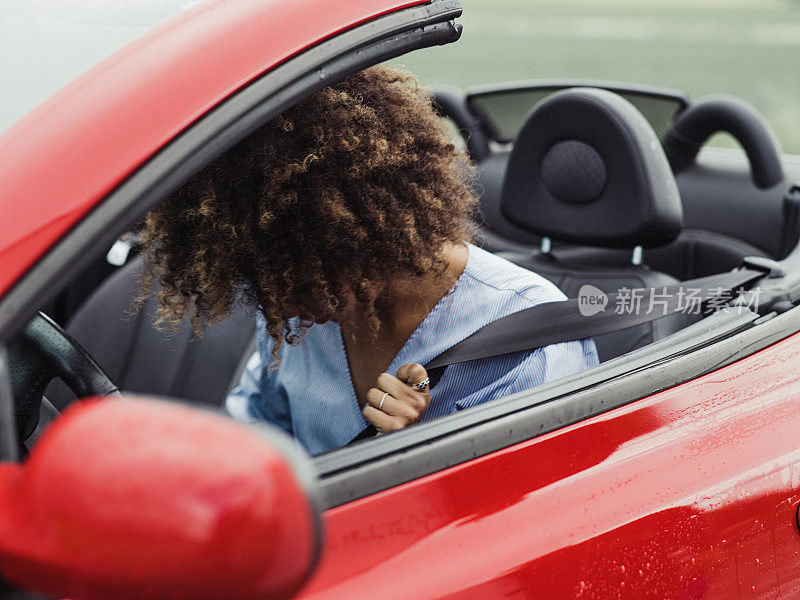 漂亮的女人开着一辆系着安全带的敞篷车