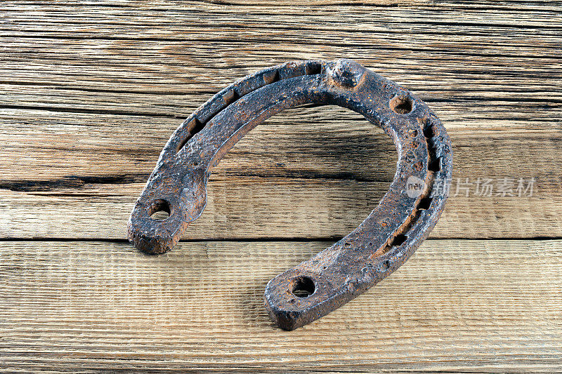 旧生锈的马蹄铁挂在木头背景上