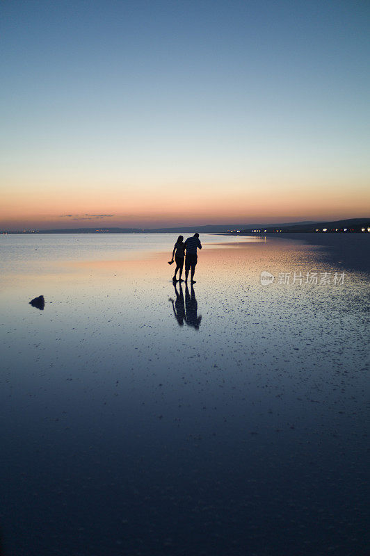 一对情侣在夏天的日落时分在土耳其科尼亚的盐湖散步