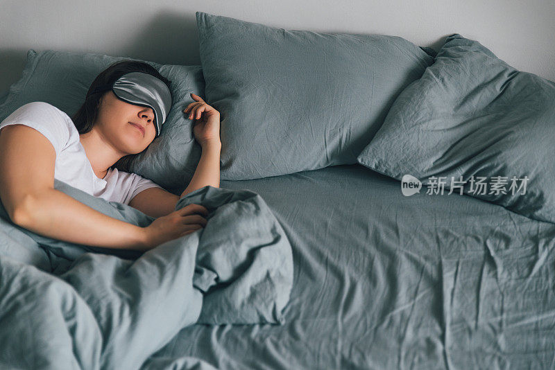 女人戴着眼罩睡在灰色的床上。本空间