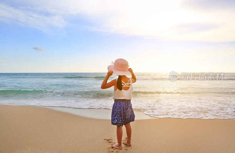 后视镜小女孩戴着草帽站在沙滩上。