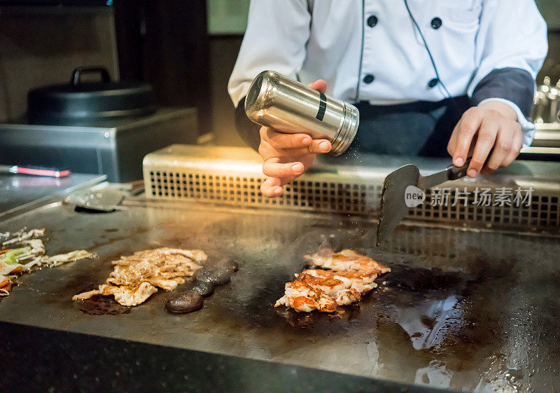 厨师在顾客面前将盐放入热锅中。日本Tepanyaki牛排