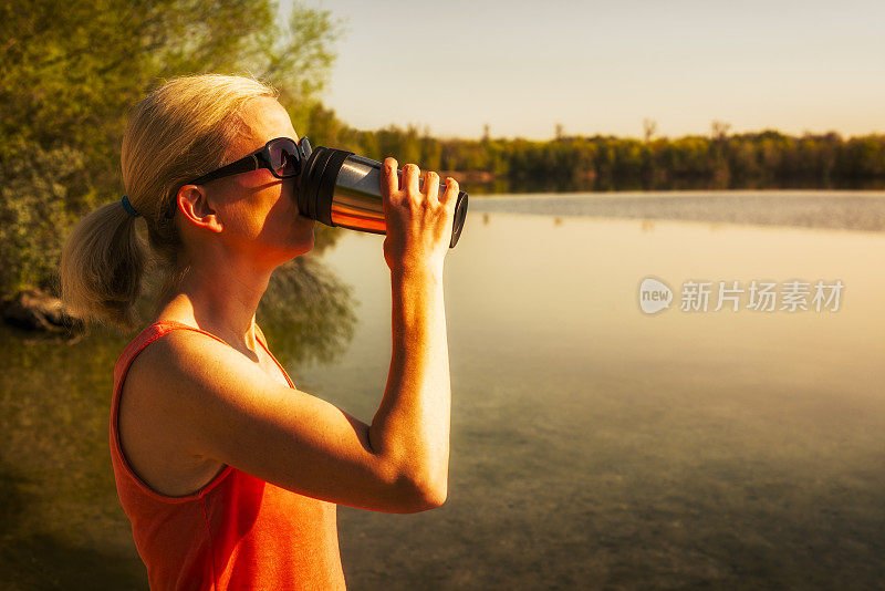 在户外用热水瓶喝水的女人