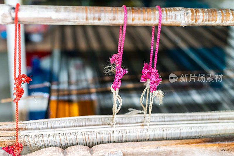 织机上的丝绸和泰国传统丝绸的特写。用于自制丝绸纺织品的织布机