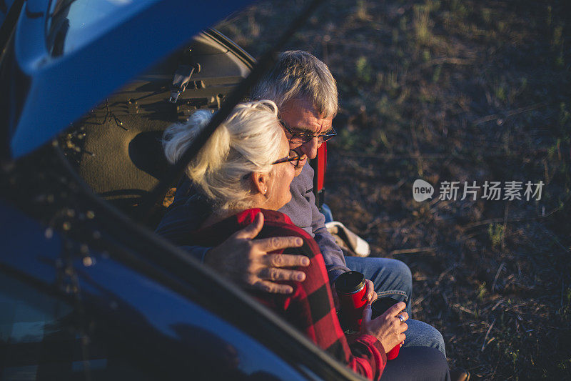 一对老年夫妇在徒步旅行前坐在敞篷汽车后备箱里