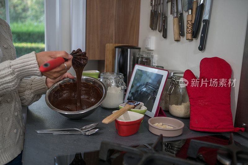 近距离女人的手烹饪巧克力蛋糕添加原料到玻璃碗，家庭制作食物的概念
