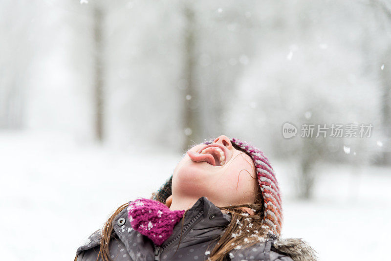 小女孩在雪中玩耍，她试图用她的嘴去接雪花