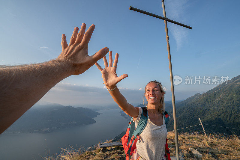 两个徒步旅行者在山顶击掌庆祝的个人视角