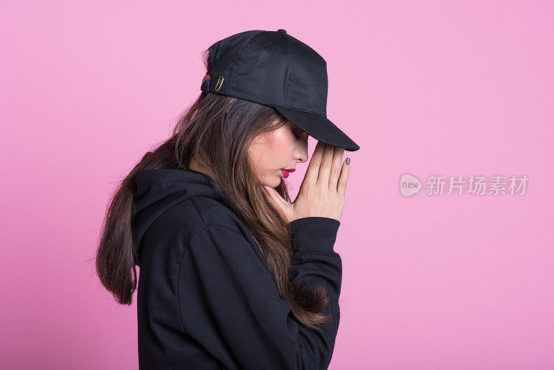 侧面的年轻女子在粉红色的背景黑衣服