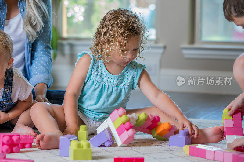 幼儿在幼儿中心的游戏室玩STEM教育玩具，老师在一旁观察。