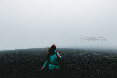 女人背包徒步旅行，虽然火山景观和风在冰岛无处