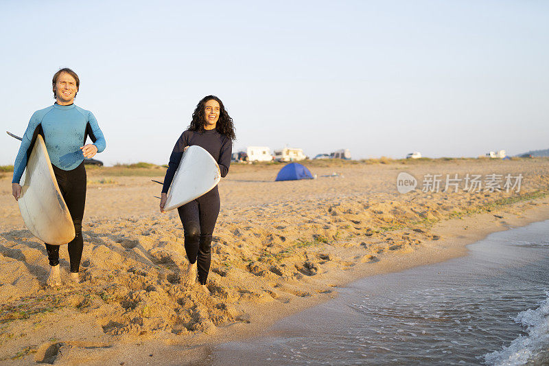 一对冲浪者手持冲浪板在沙滩上行走