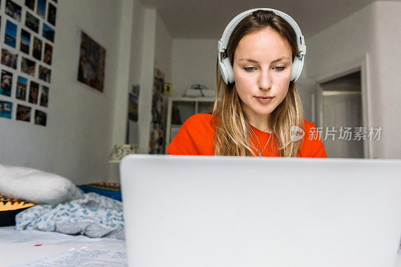 年轻女子戴着耳机在笔记本电脑前