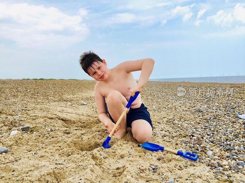 男孩在海滩上挖东西