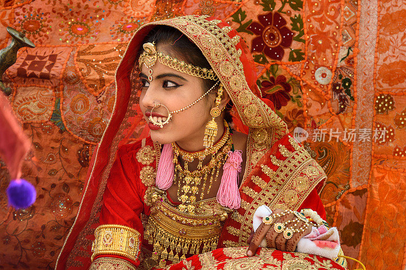 在Jaisalmer沙漠节上，身着红色纱丽并饰以传统印度珠宝的印度女孩。拉贾斯坦邦。印度
