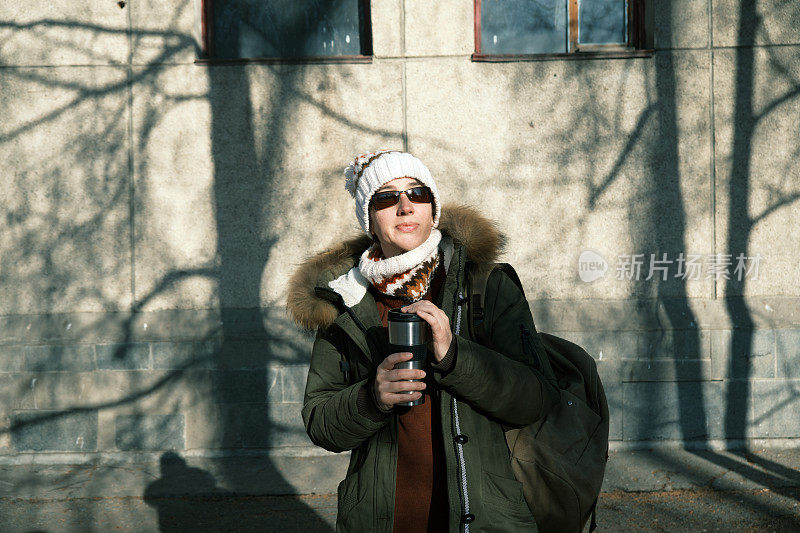 冬日城市公园里，一名女子正在用热水杯喝热茶