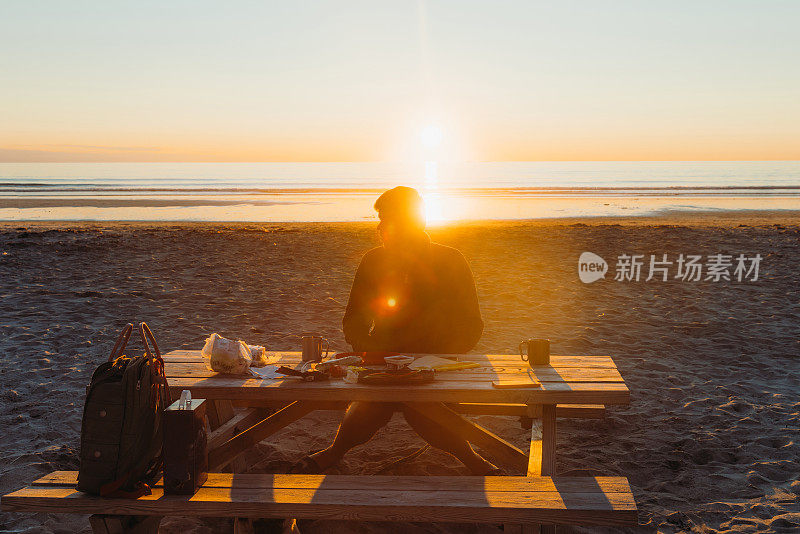 在罗浮敦群岛的午夜阳光下，男子在风景优美的海滩露营和野餐