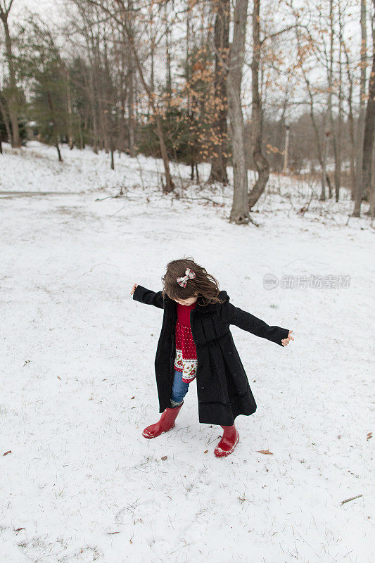 2022年12月，俄亥俄州杰克逊，一个3岁的古巴裔美国学步女孩在寒冷的雪天穿着外套、靴子和蝴蝶结，在新鲜的白色蓬松的雪中度过圣诞节