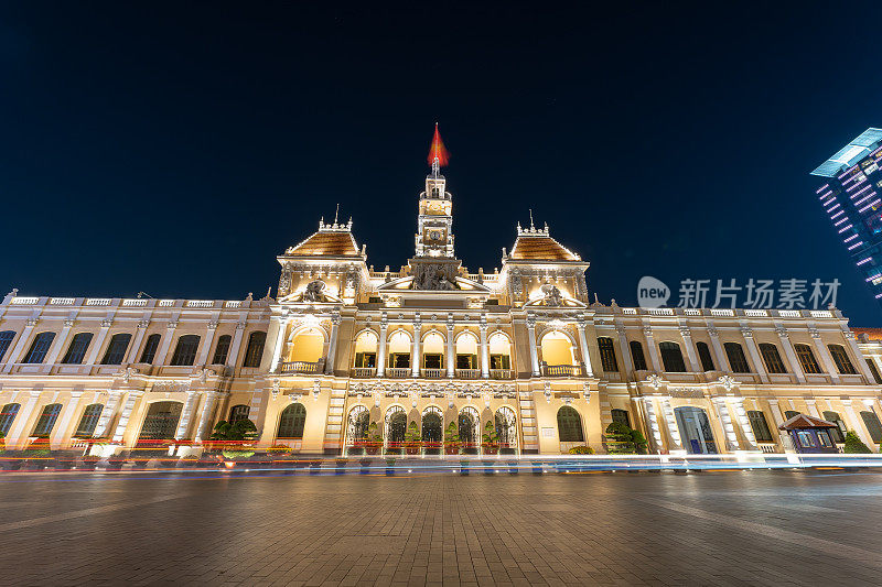 交通在胡志明市政厅，西贡市政厅或委员会总部在晚上，越南。轻盈的小径和夜晚。西贡最受欢迎的旅游景点