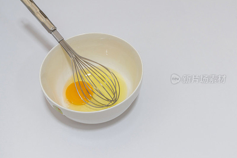 白色背景的蛋碗和打蛋器