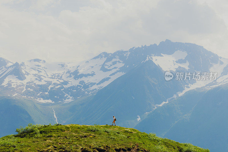 女子在远距离徒步旅行与背景风景秀丽的森莫尔阿尔卑斯山在挪威