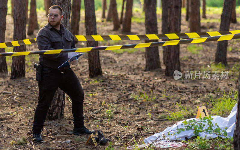 年轻的侦探在森林里的犯罪现场，看着受害者的尸体，检查证据，开始他的调查。
