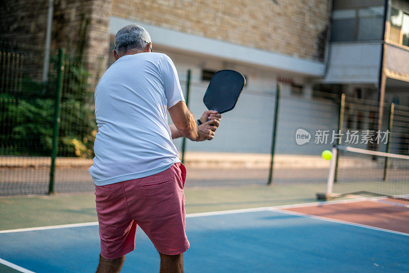 高级男子匹克球运动员反手从背后射击水平运动的观点仍然