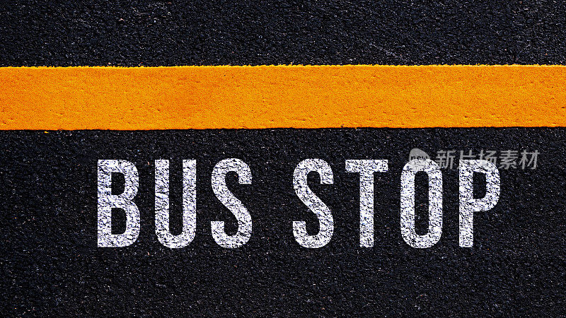 公交站牌文字和黄线写在柏油路中间，公交站牌文字写在街道上。