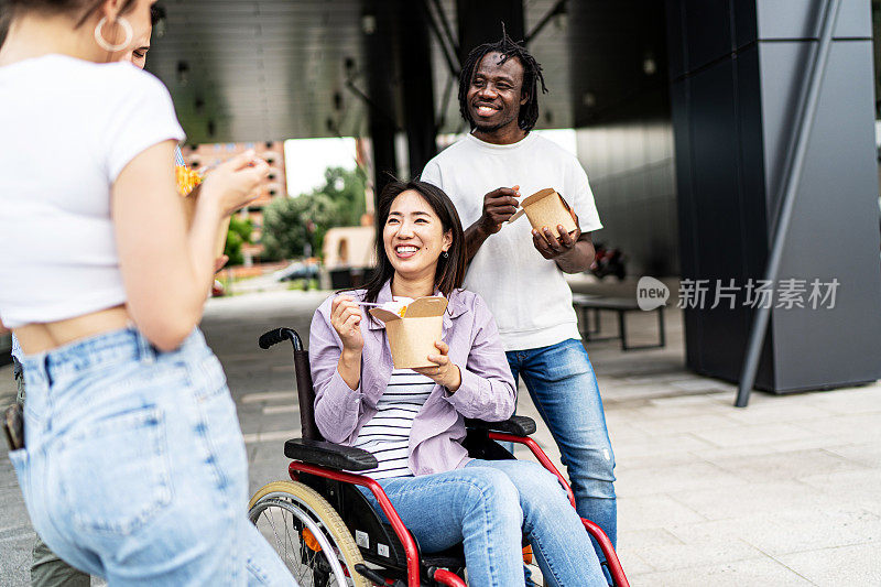 坐在轮椅上的年轻女子在户外和她的朋友们有说有笑