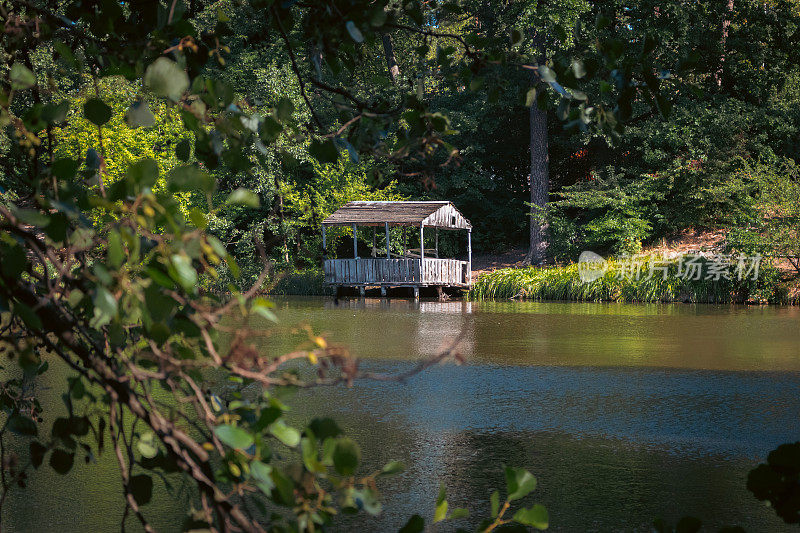 河岸上的木屋。有湖和木屋的秋林。秋季休闲活动。如画的秋景。有池塘和小房子的乡村。非城市生活概念。