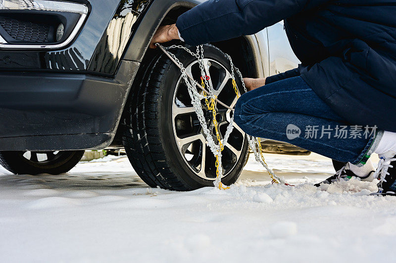 一个男人在冬天给车轮装上链条的低角度照片。