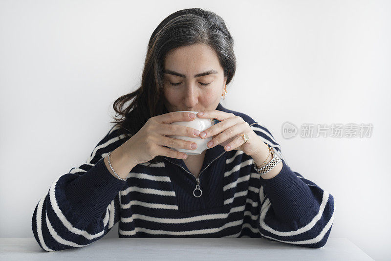 一个女人闭着眼睛闻咖啡的味道