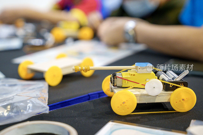 这张特写展示了一名学生勤奋地在DIY机器人汽车上工作，捕捉到了编码、技术、机器人和科学的本质。