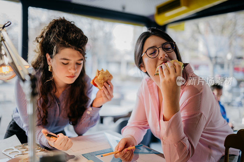 年轻的建筑师正在吃美味的三明治