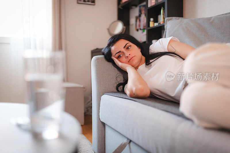 年轻女子躺着，肚子疼得难受