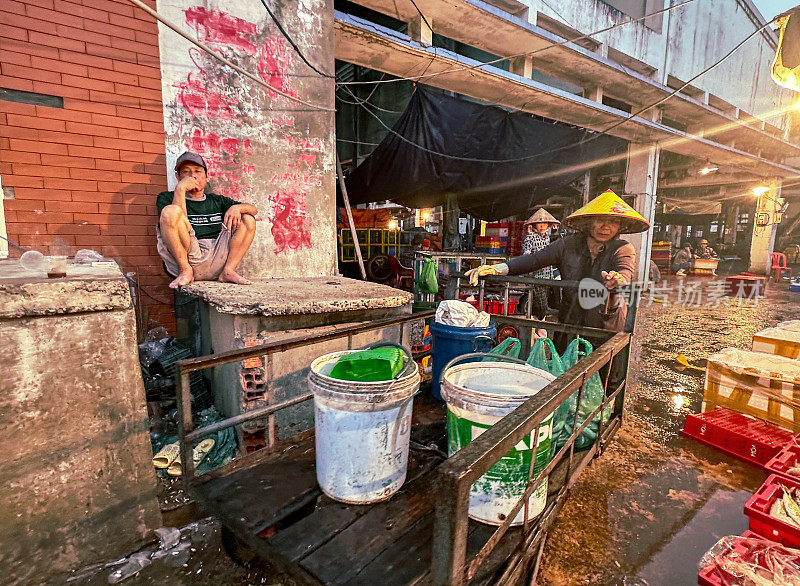 越南桂仁海鲜市场，卖鱼的人向顾客展示鱼