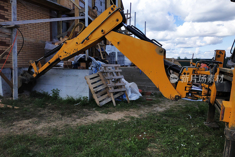 挖掘机在一栋正在施工的建筑物周围挖洞。