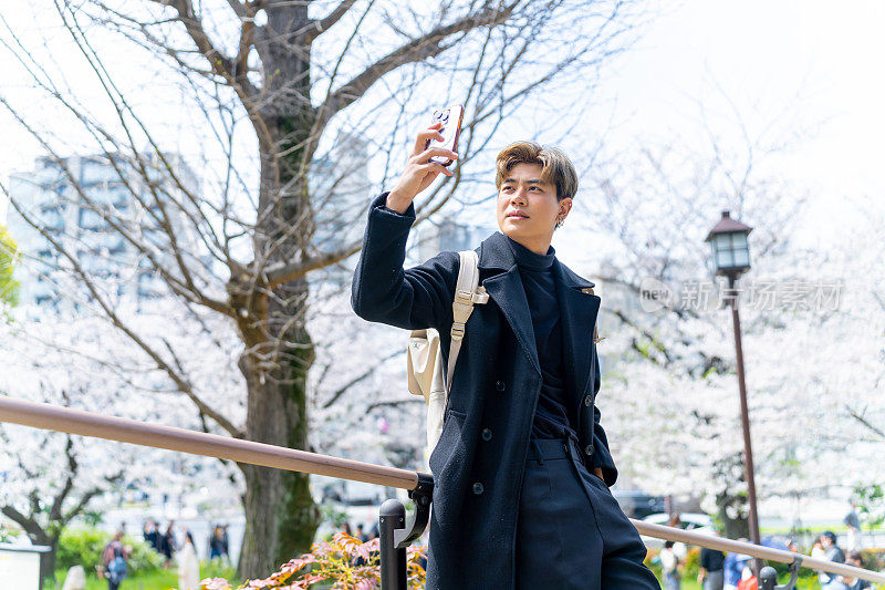一名亚洲男子在日本东京旅行时用手机自拍。