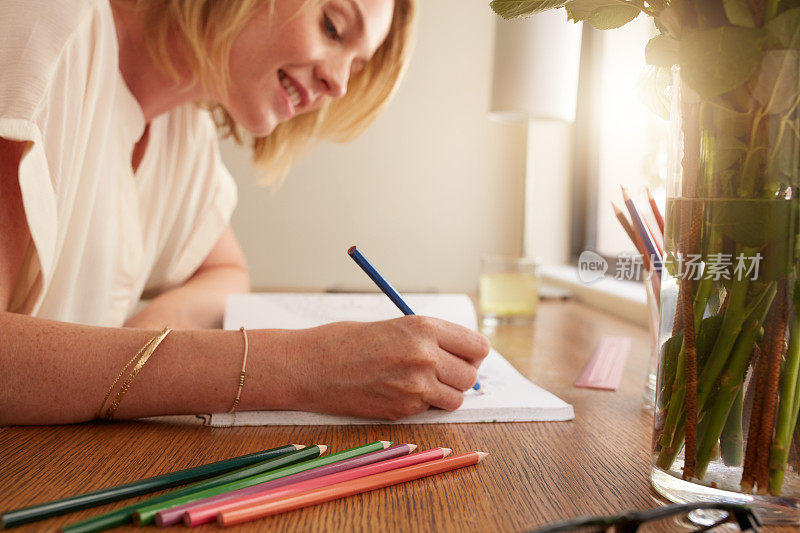 一个女人用铅笔在一本成人涂色书上涂色