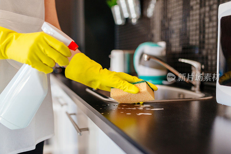 用海绵和喷雾清洁剂清洁厨房橱柜的女人