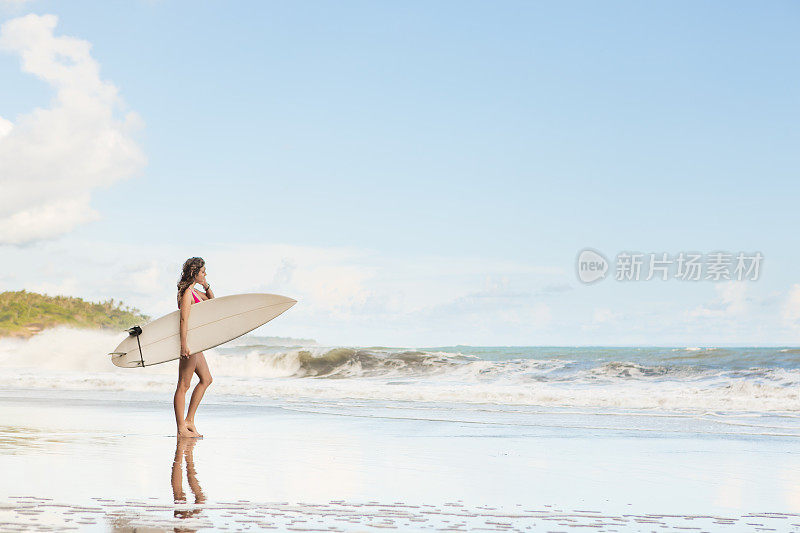 美丽的长发女孩在海滩上冲浪